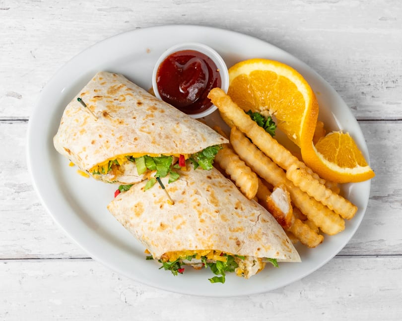 Chicken wrap with lettuce, cheese, and red peppers, served with fries, orange slices, and ketchup.